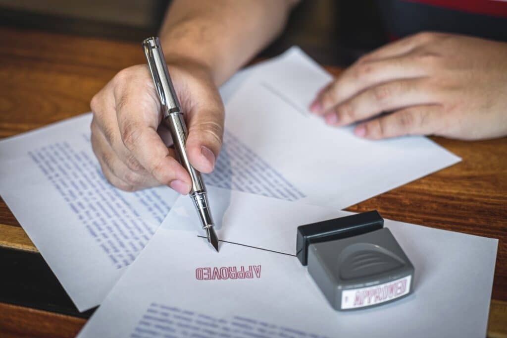 Retificação de Registro Civil - pessoa segurando uma caneta, apoiada em um documento carimbado