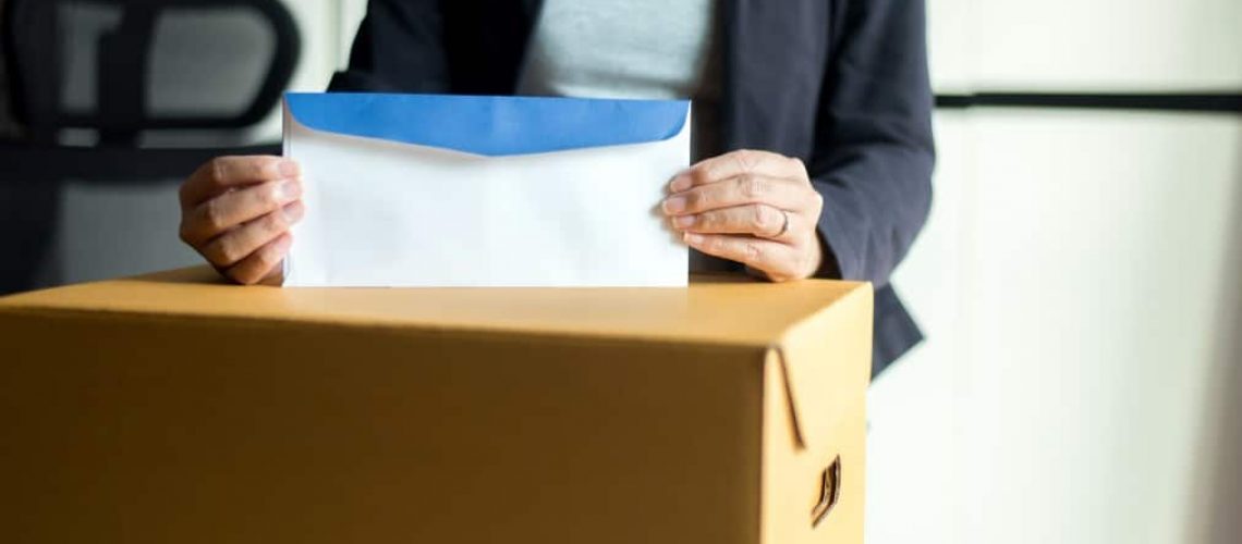 causas de rescisão indireta do contrato de trabalho - mulher segurando envelope sobre uma caixa