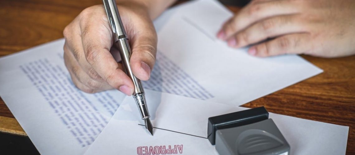 Retificação de Registro Civil - pessoa segurando uma caneta, apoiada em um documento carimbado